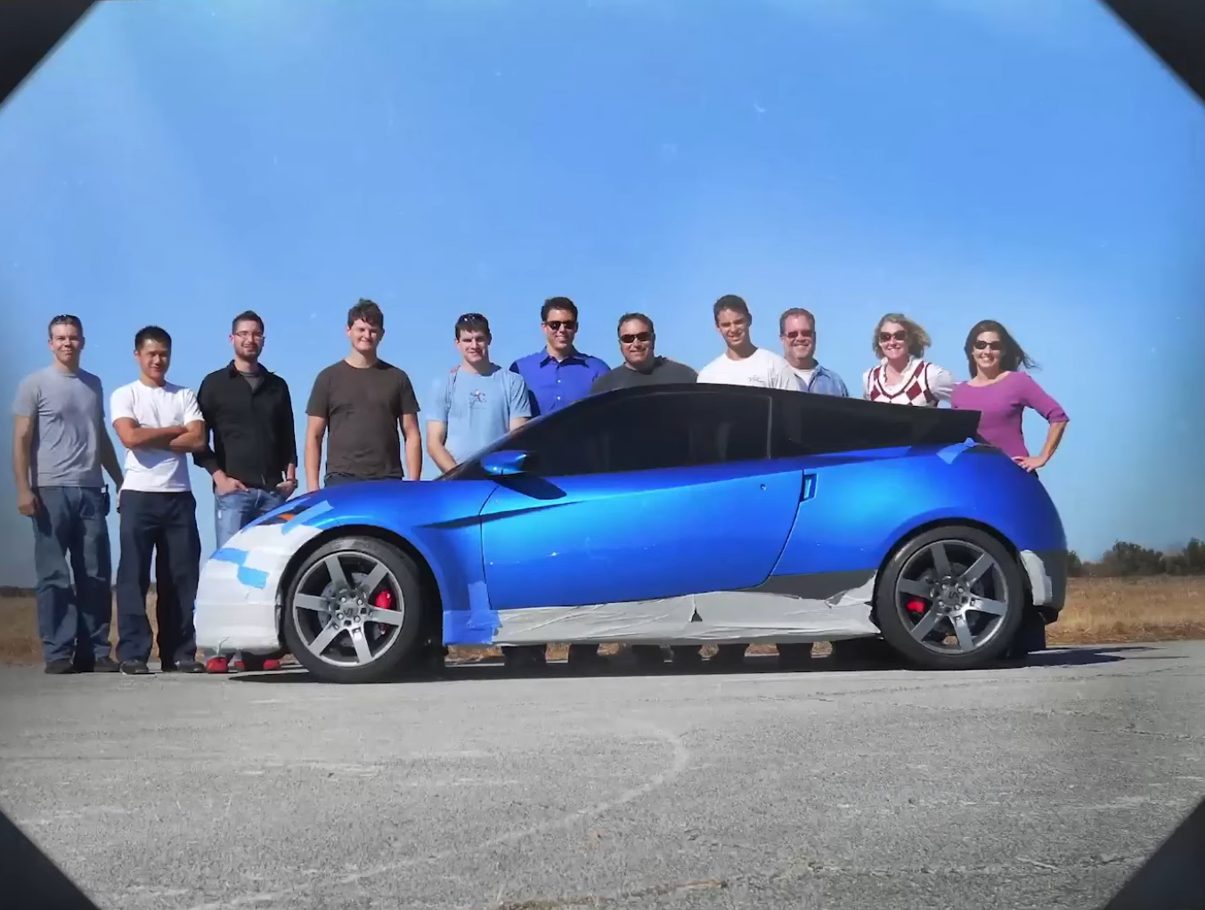 The blue Rivian sports car prototype, shot in profile with employees standing behind it