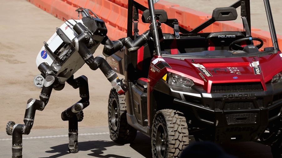 A Nasa robot entering a Polaris vehicle to drive it