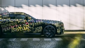 A black and livery with gold text laid over the bodywork of the new Rolls Royce Spectre luxury car