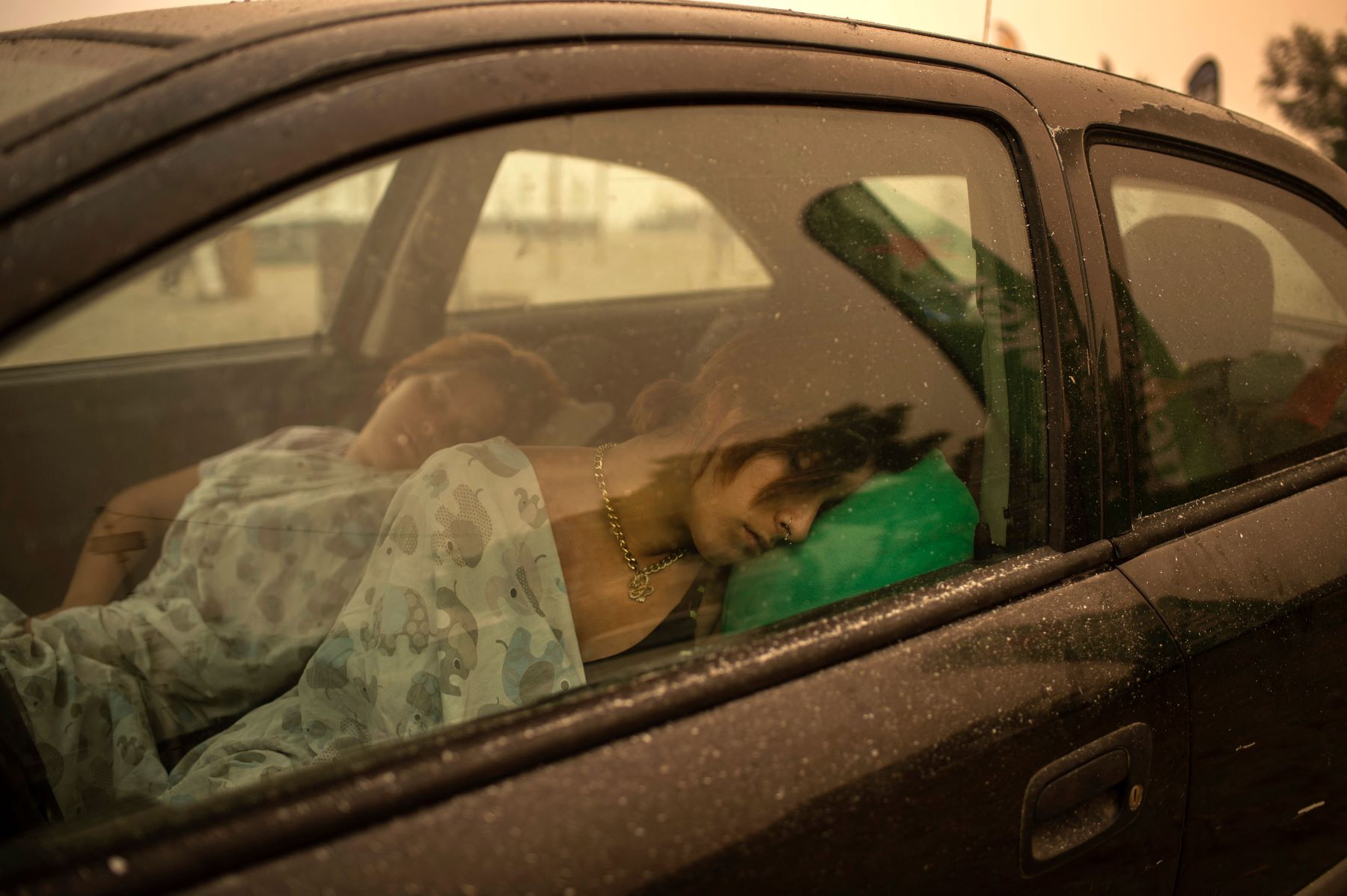 A woman and child sleeping in a car in the Pefki village of Euboea, Italy