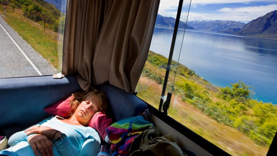 A woman sleeping in the back of an RV during a trip in South Island, New Zealand