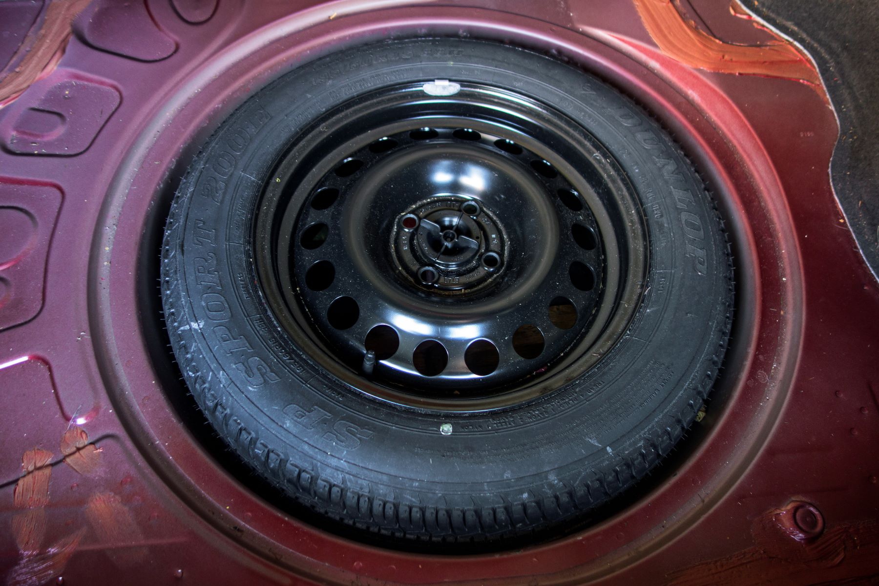 A full-size spare tire stowed in the trunk of a car