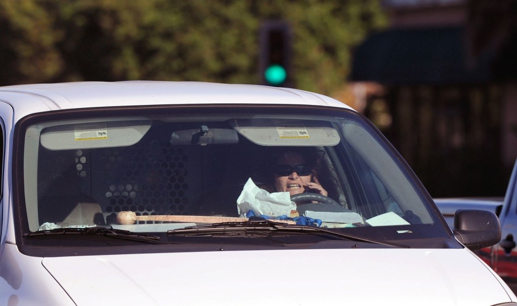 A distracted woman driver eating and talking on the phone in Long Beach, California