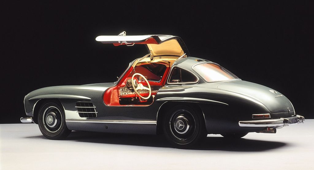 The side 3/4 view of a green 1954-1957 Mercedes 300SL Gullwing coupe with its driver door up