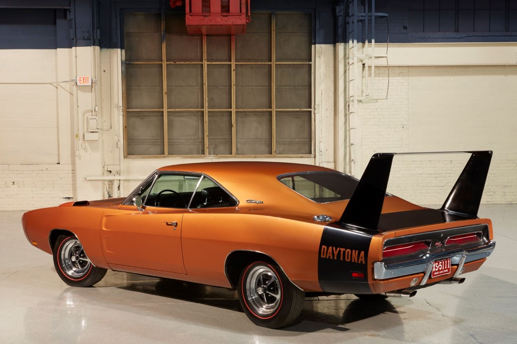 The rear 3/4 view of an orange-and-black 1969 Dodge Charger Daytona in a garage