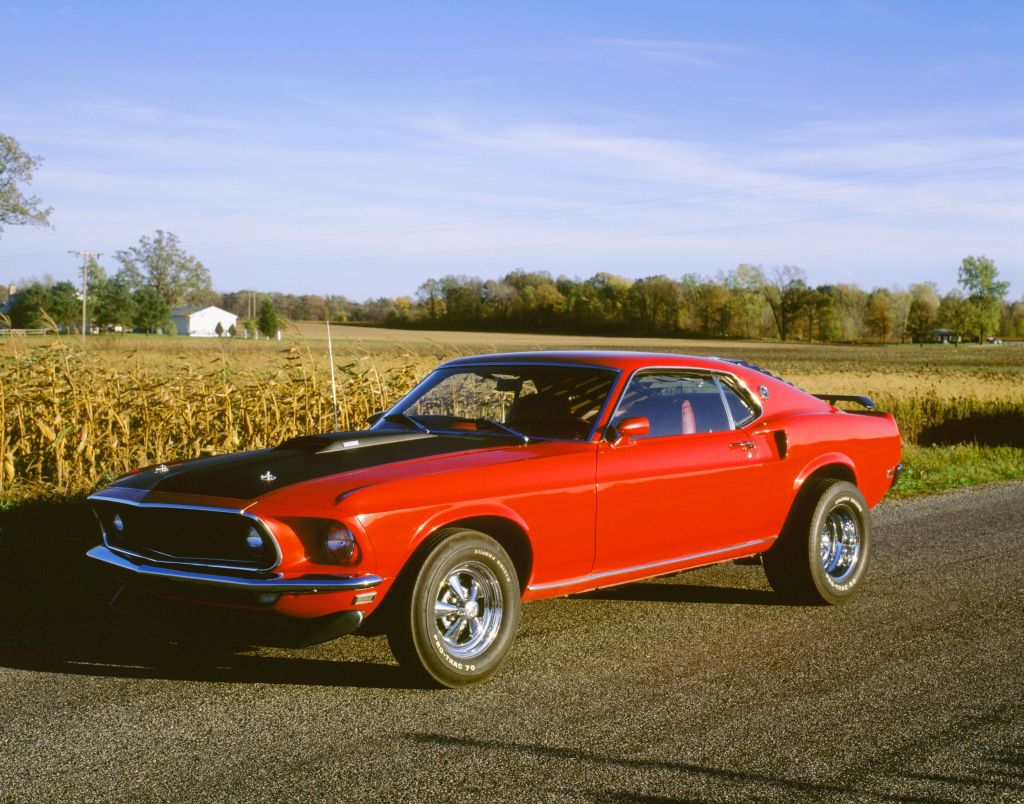 A red-and-black 1969 Ford Mustang Mach 1 on a country road