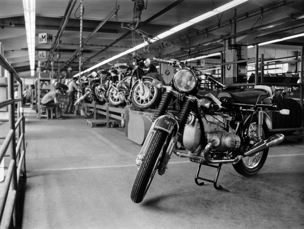 An unfinished black 1972 BMW R75/5 sits among other unfinished motorcycles at the BMW factory