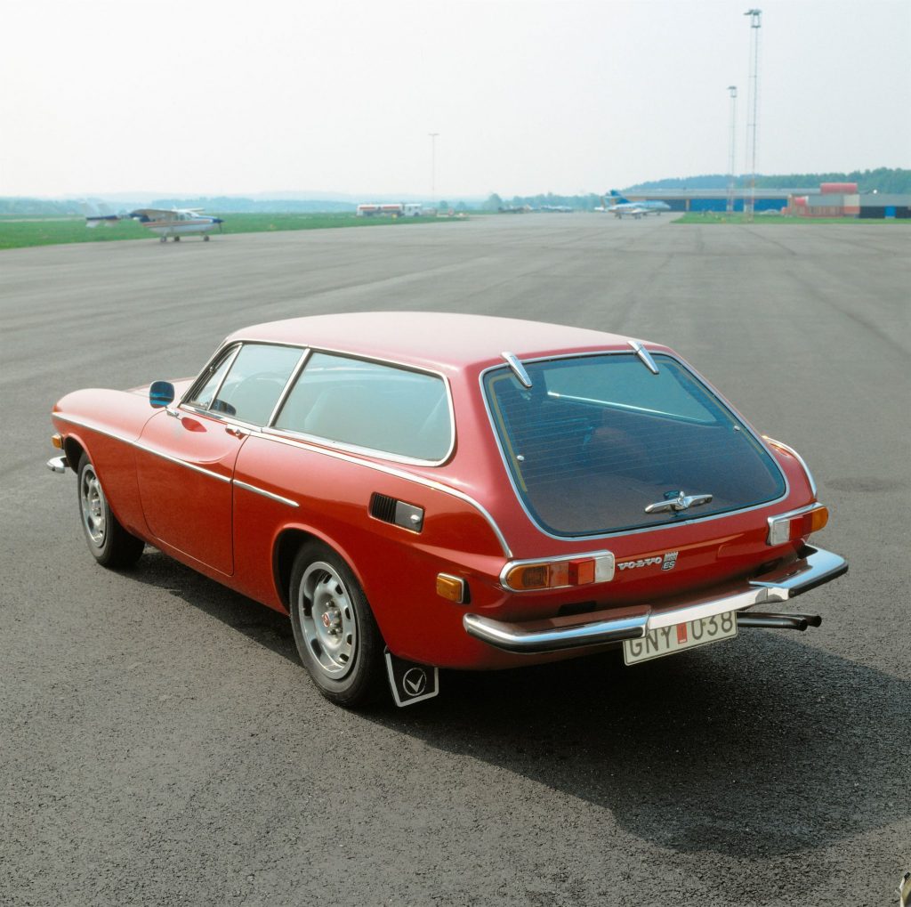 The rear 3/4 view of a red 1972 Volvo 1800ES on an airport runway