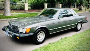 A gray 1981 C107 Mercedes 380 SLC parked on a city street