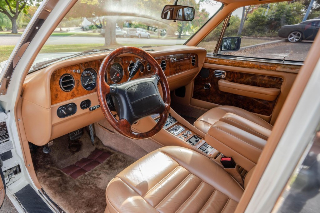 The tan-leather-upholstered front seats and wood-trimmed dashboard of a white 1990 Bentley Turbo R