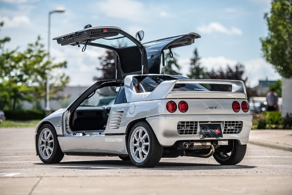 The rear 3/4 view of a silver 1993 Autozam AZ-1 Mazdaspeed with its gullwing doors up