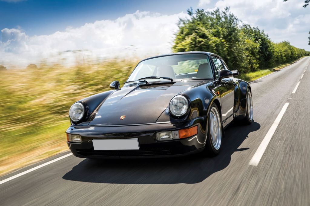 A brown 1993 Porsche 964 911 Turbo 3.6 driving down the road