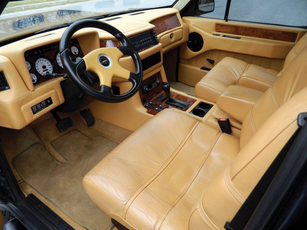 The tan-leather-upholstered front seats and tan-leather-and-wood-trimmed dashboard of a 1998 Laforza Magnum Edition