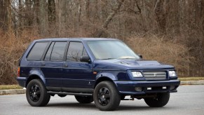 A dark-blue 1998 Laforza Magnum Edition in a parking lot by a forest