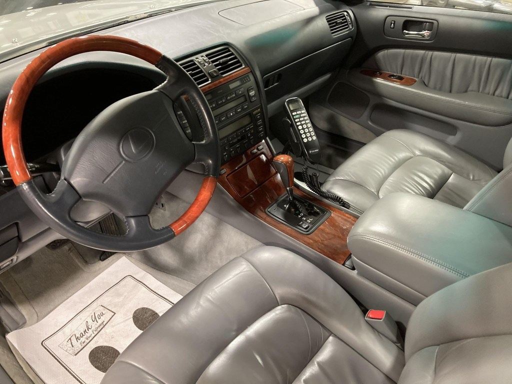 The gray-leather front seats and gray dashboard of a 1999 Lexus LS 400 with an aftermarket phone
