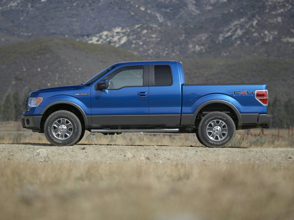 A blue 2012 Ford F-150 parked outside near grass