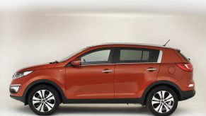 An orange 2013 Kia Sportage with a white background, it is one model year that should be avoided.