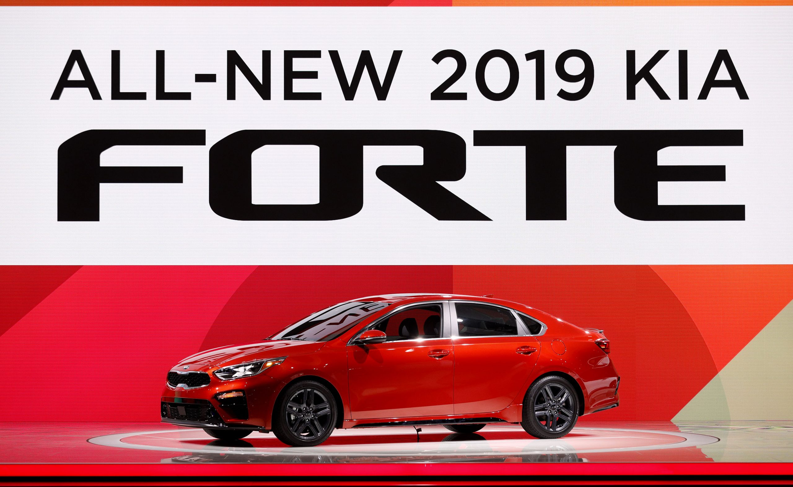A red 2019 Kia Forte on stage at an auto show shot from the 3/4 angle