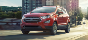 The 2021 Ford EcoSport subcompact SUV in red driving over a bridge in an urban city