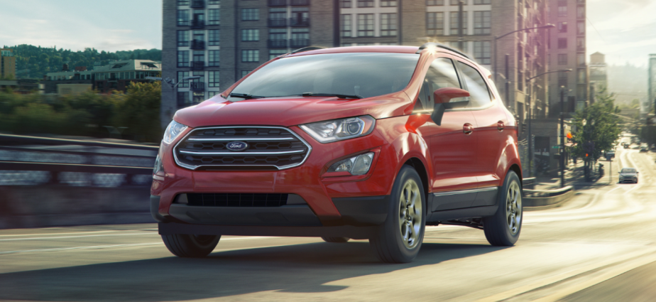 The 2021 Ford EcoSport subcompact SUV in red being driven on a bridge in an urban city. 