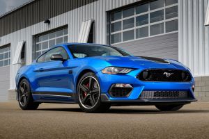 The 2021 Ford Mustang Mach 1 sports muscle car in blue parked outside of a warehouse garage