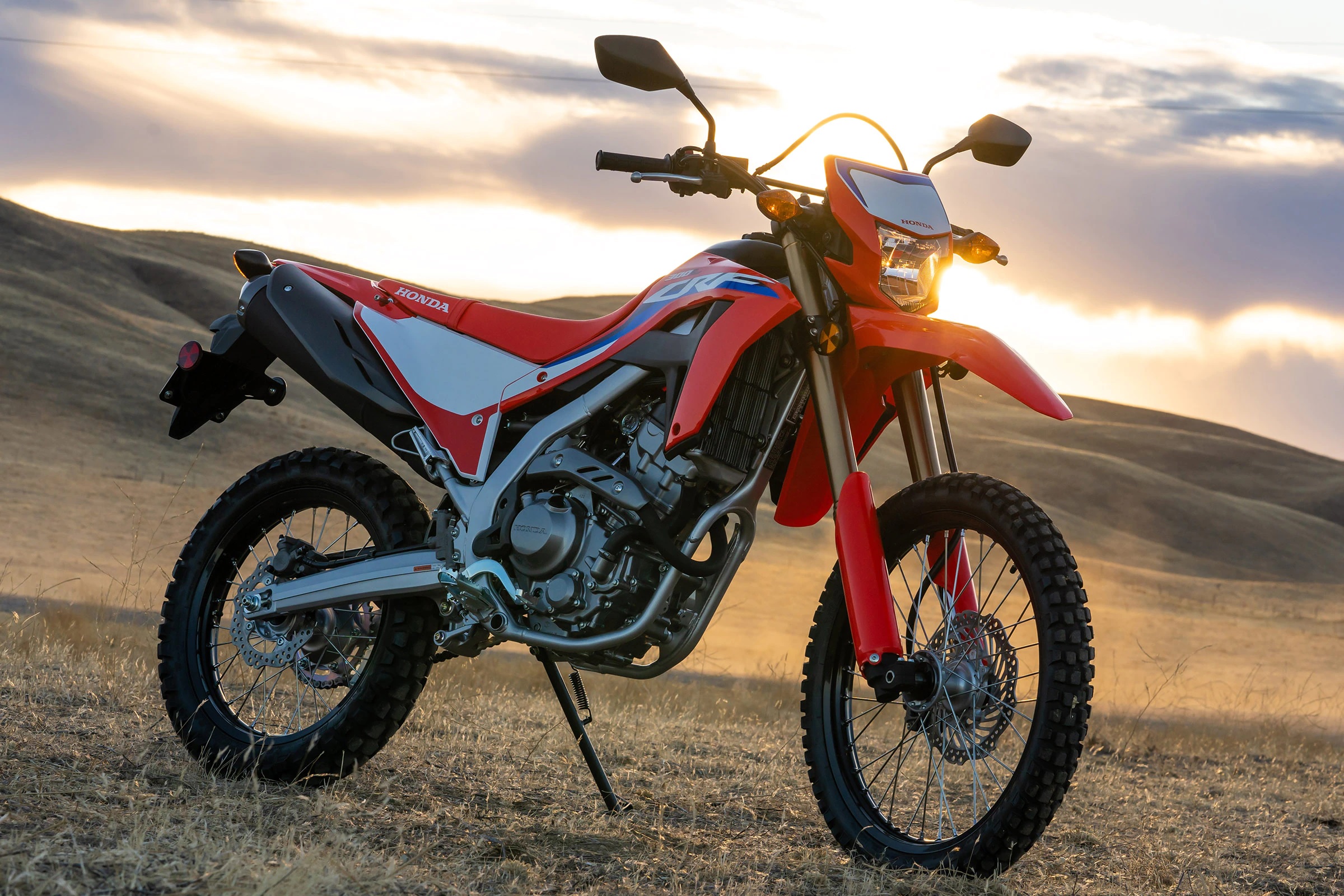 A red-and-white 2021 Honda CRF300L dual-sport motorcycle amongst desert plains