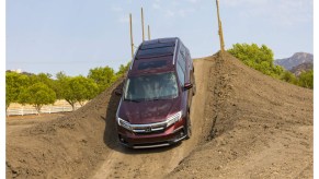 A maroon 2022 Honda Pilot drives off-road in the dirt, it's more expensive for the new model year.