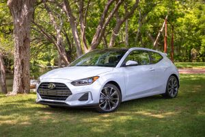 The 2021 Hyundai Veloster compact performance hatchback model in white parked in a park forest