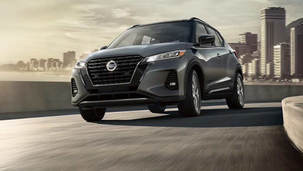 A gray 2021 Nissan Kicks driving away from a city background