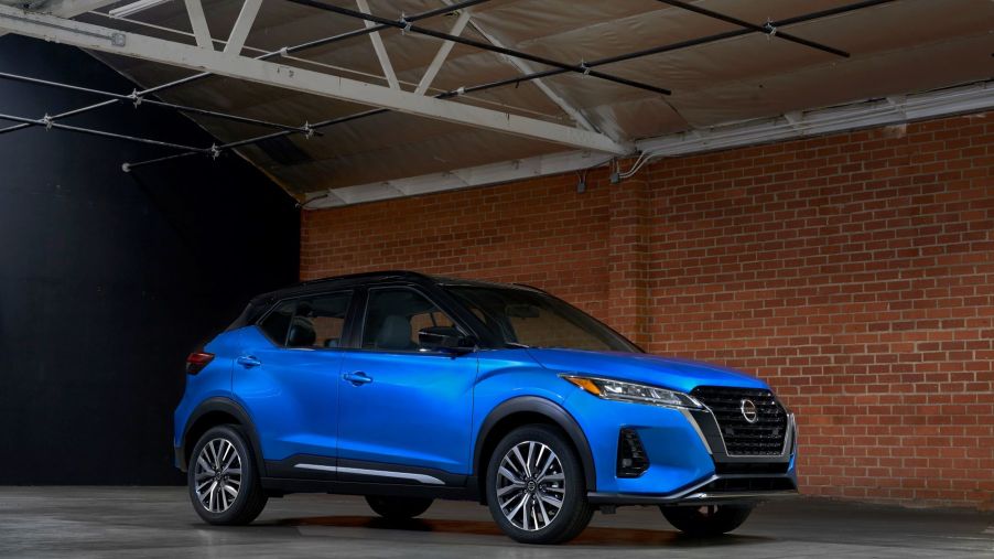 The 2021 Nissan Kicks subcompact SUV with a blue body and black roof parked in a brick warehouse