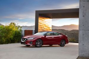 The 2021 Nissan Maxima full-size sedan in red parked outside of a luxury home