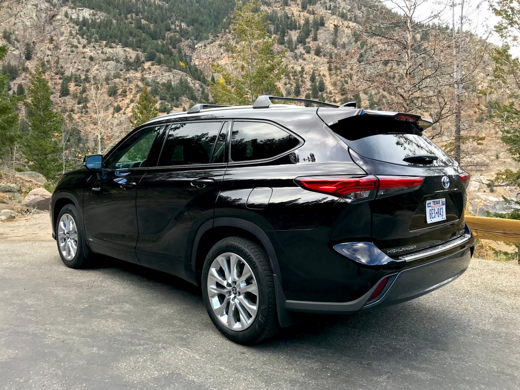 A rear three-quarter shot of the 2021 Toyota Highlander Hybrid in black on a mountain road.