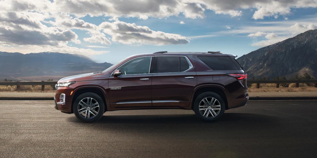 A maroon 2022 Chevy Traverse High Country midsize SUV is parked on the road, it received a few new features this model year.
