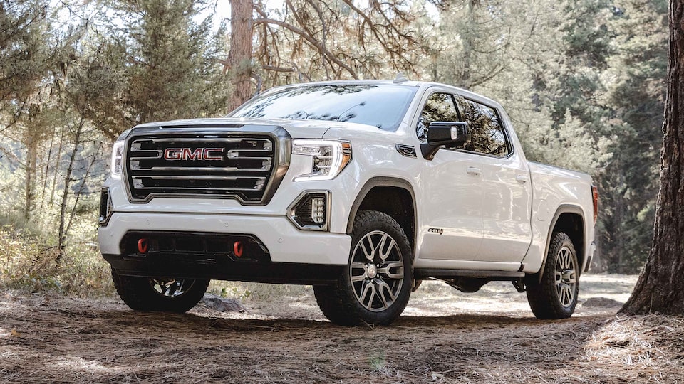 A white 2022 GMC Sierra AT4 is parked in the woods, it's made for off-roading.