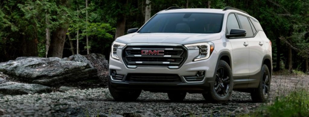 The 2022 GMC Terrain compact SUV parked on a pebble beach of rocks within a forest