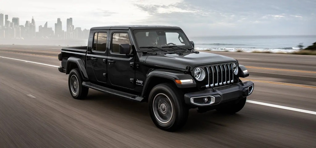 A black 2022 Jeep Gladiator pickup truck driving down a coastal highway.