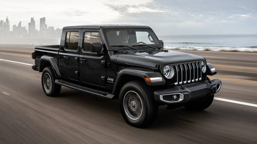 A black 2022 Jeep Gladiator driving down a coastal highway.