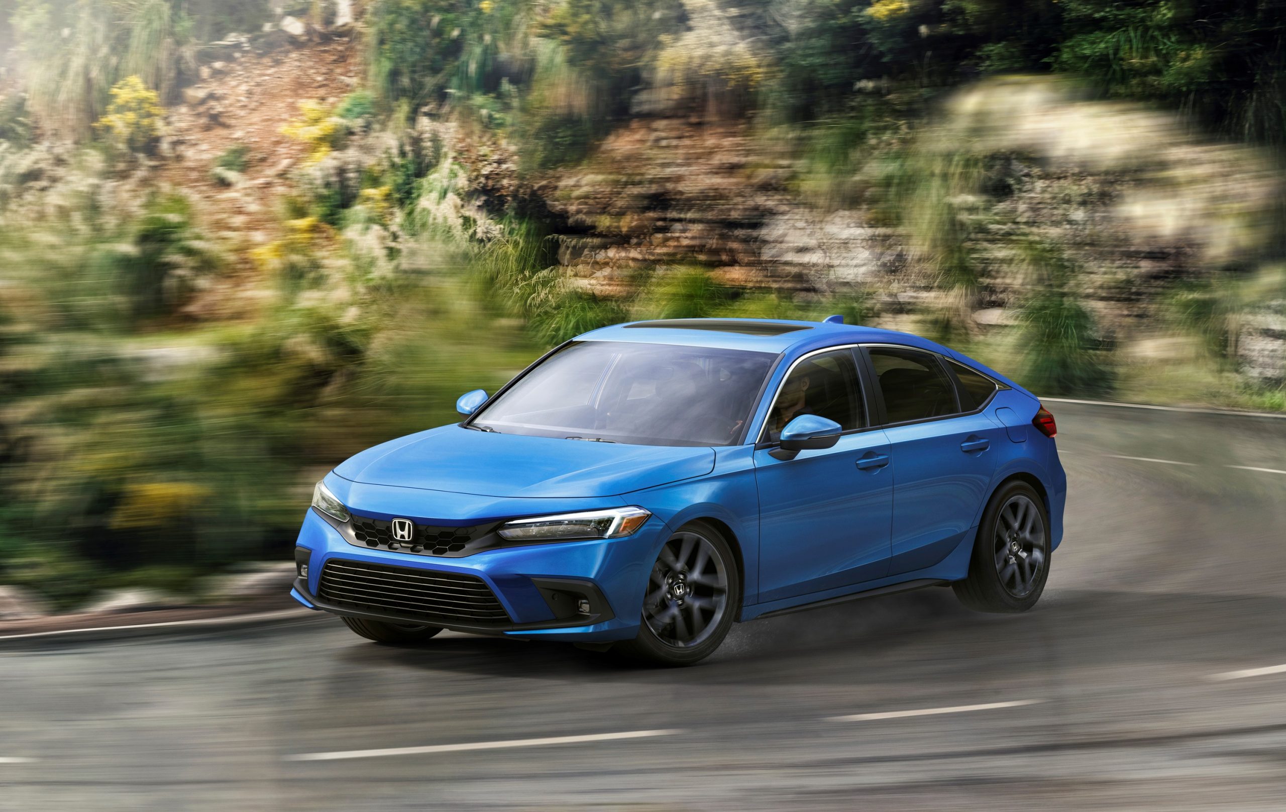 A blue 2022 Honda Civic hatchback shot in motion from the front 3/4