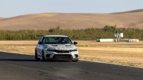 A camouflaged Honda Civic Si makes its way down the straight at a race track