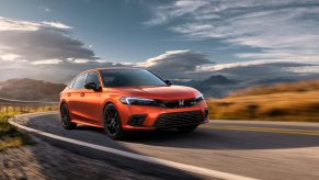 A blaze orange 2022 Honda Civic Si shot from the front 3/4 on a back road