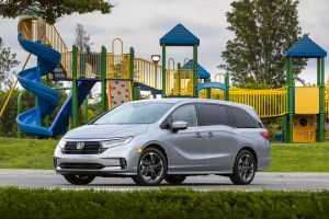 The 2022 Honda Odyssey minivan in silver gray parked near a children's playground park