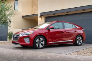 The 2022 Hyundai Ioniq Hybrid hatchback in a red paint color option parked outside a closed garage on a cobblestone tile driveway