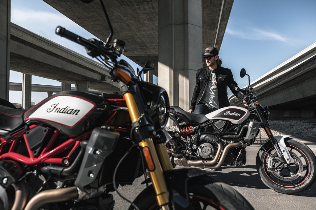 A black-white-and-red 2022 Indian FTR R Carbon in front of a white-and-black 2022 Indian FTR S under a city bridge