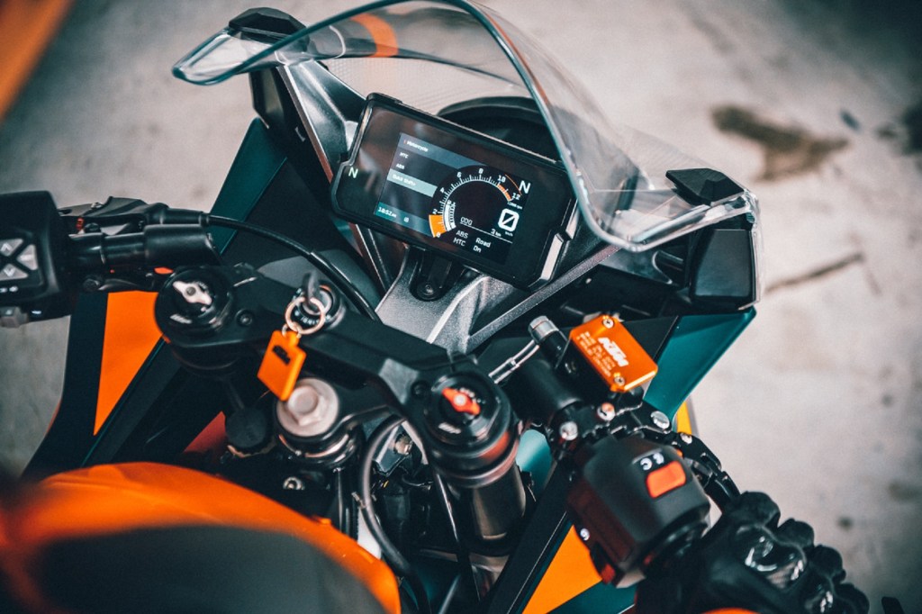 The TFT dash and clip-on handlebars on an orange-and-black 2022 KTM RC 390