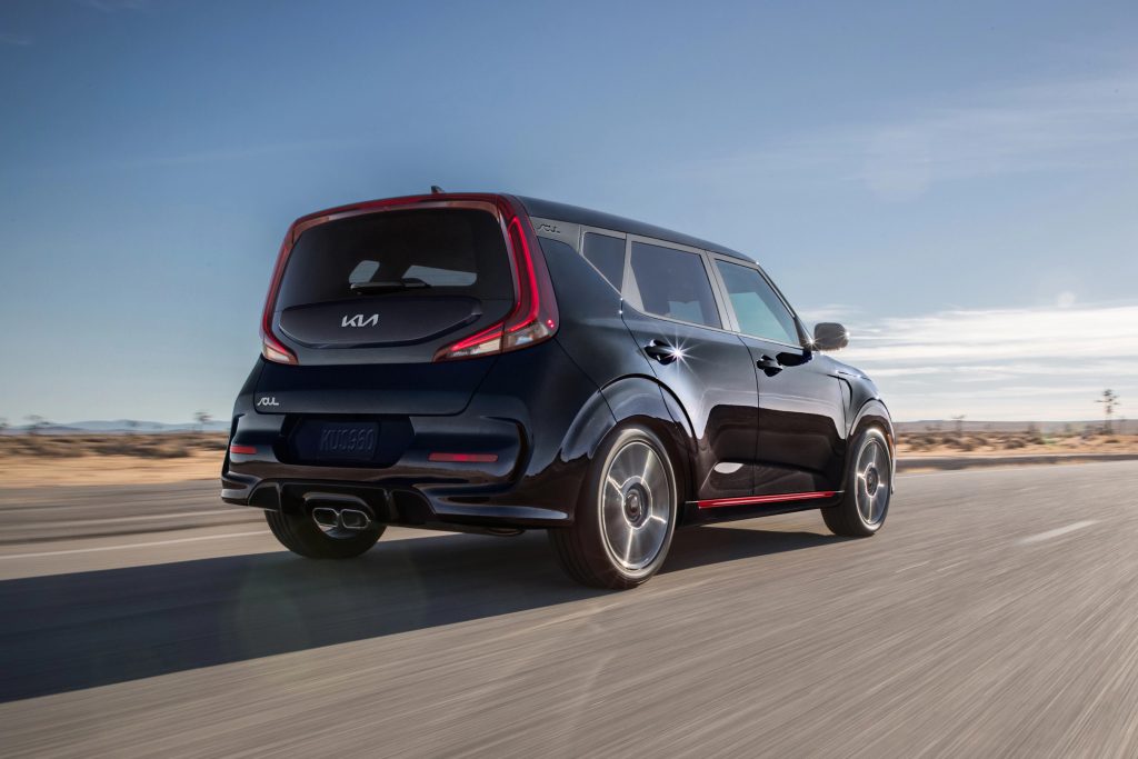 A black 2022 Kia Soul drives on a road during the day