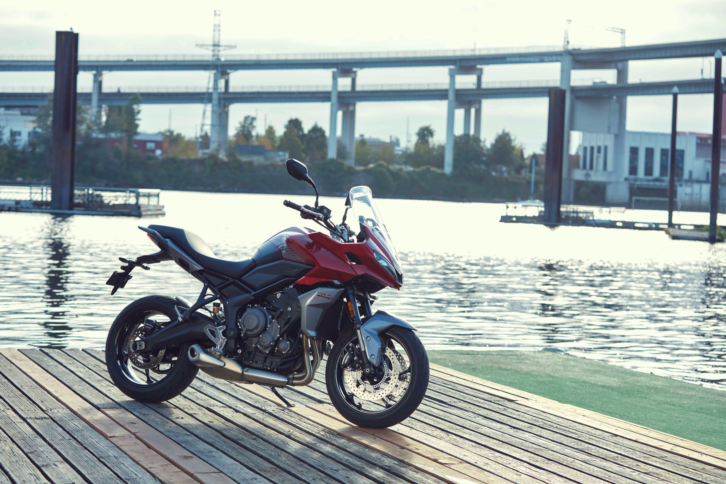 A red-black-and-silver 2022 Triumph Tiger Sport 660 parked by a city river