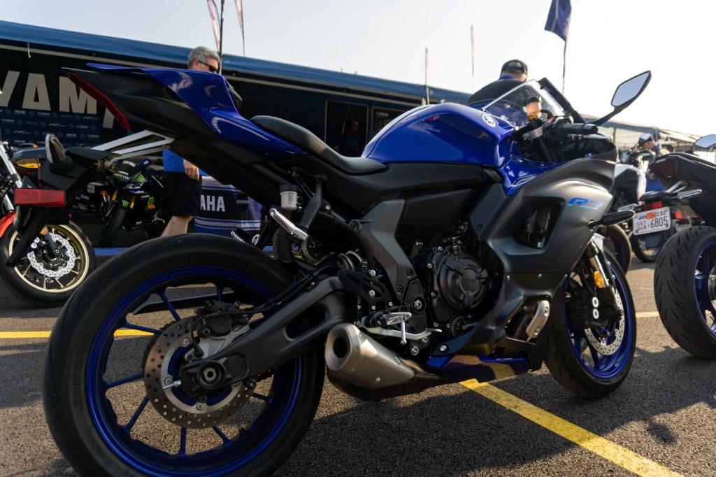 The rear side 3/4 view of a blue-and-black 2022 Yamaha YZF-R7 in a parking lot