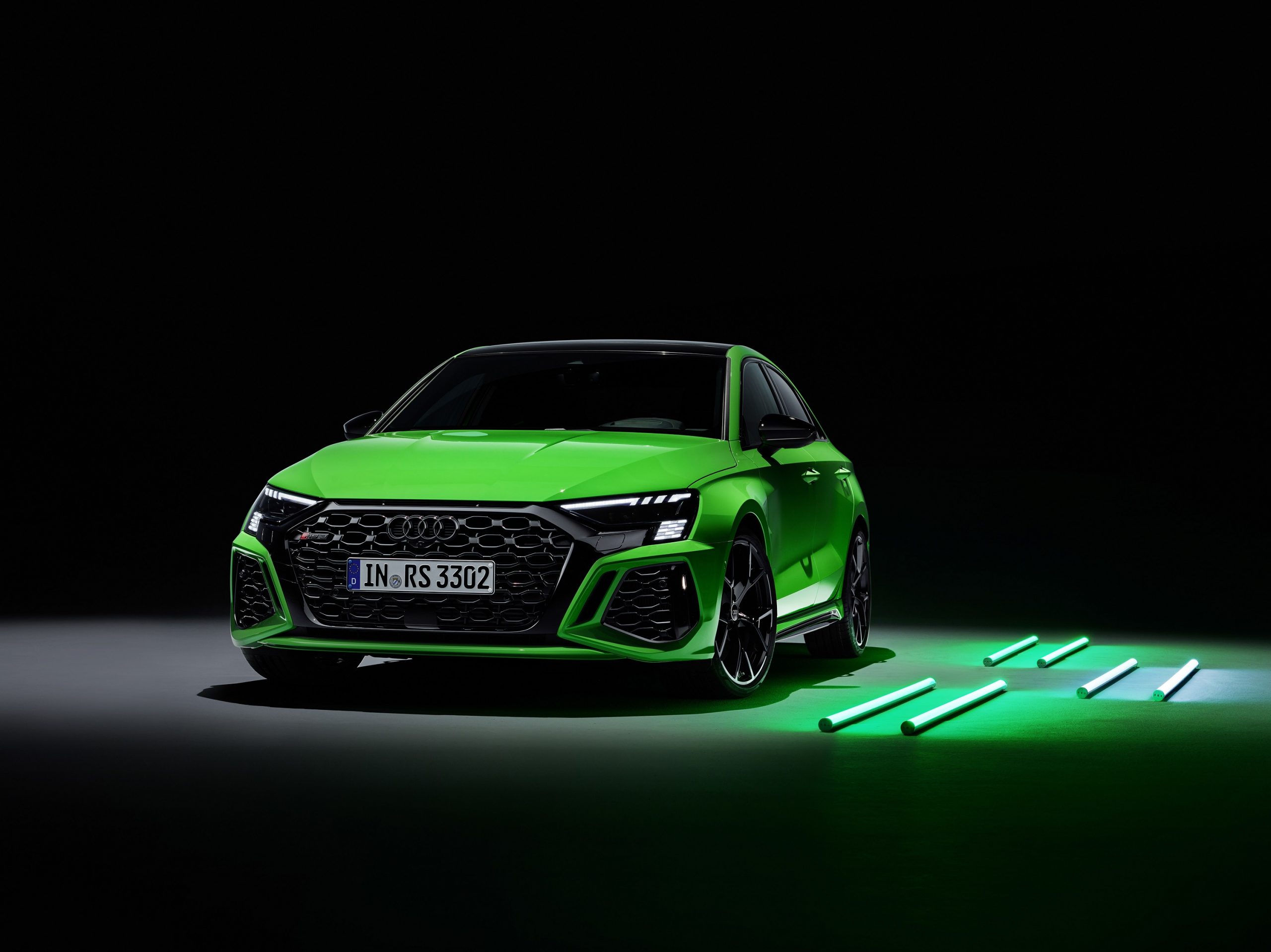 A bright green Audi RS3 shot from the front in a studio booth
