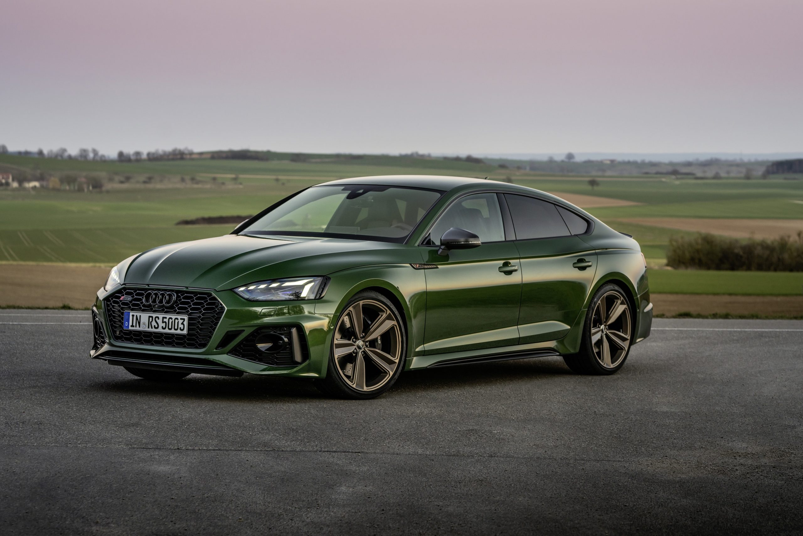 A Sonoma Green Audi RS5 sportback shot from the 3/4 angle at sunset