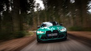 The 2022 BMW M3 Competition in Isle of Man Green shot from the front of a forested road